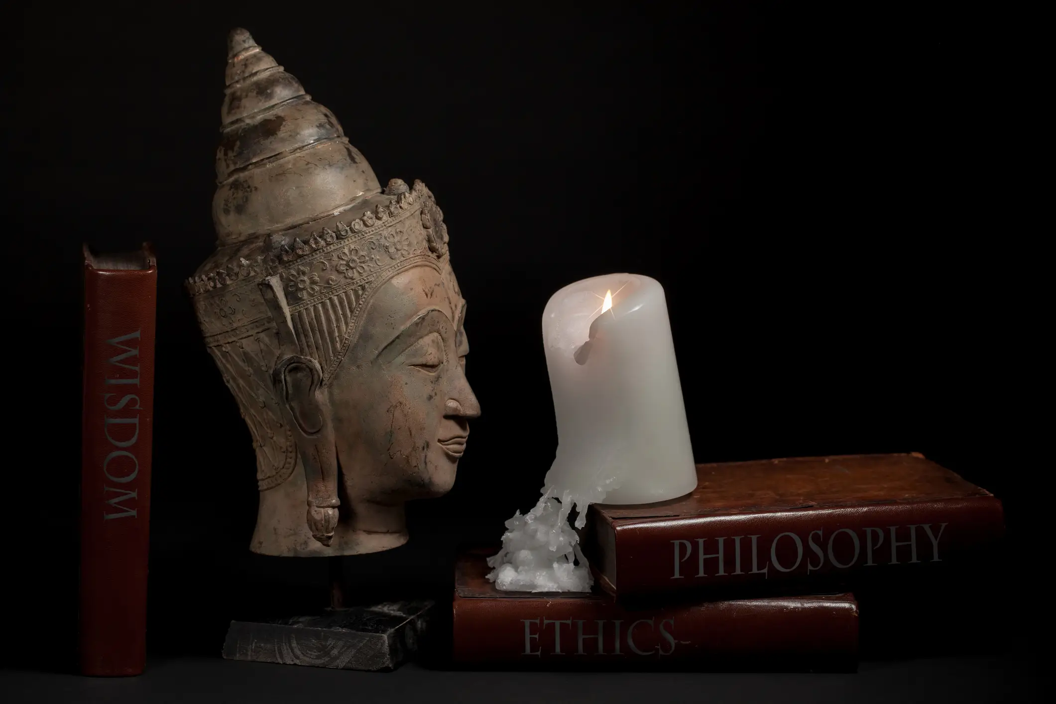 Buddha head, candle, and philosophy books.