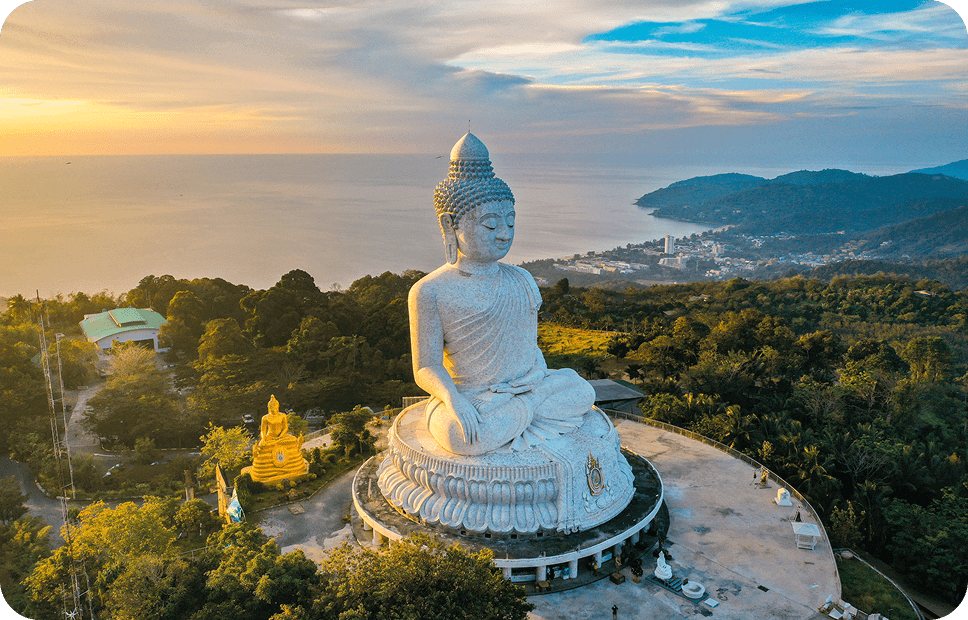 Large Buddha statue overlooking ocean and hills.