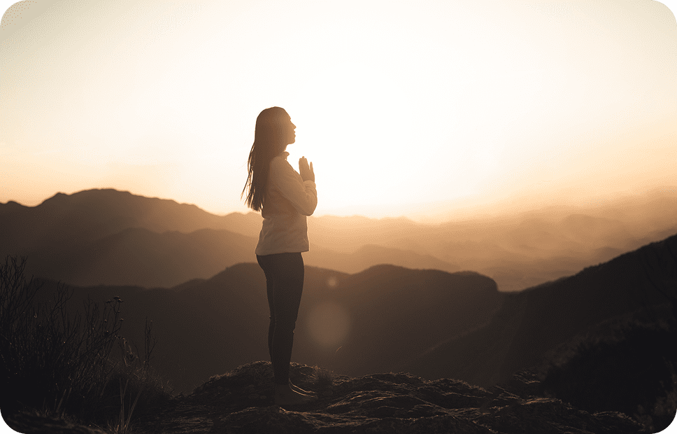 Person meditating at sunrise on mountain.