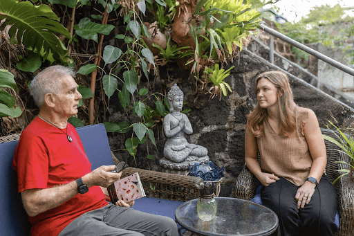 Two people talking by garden Buddha statue
