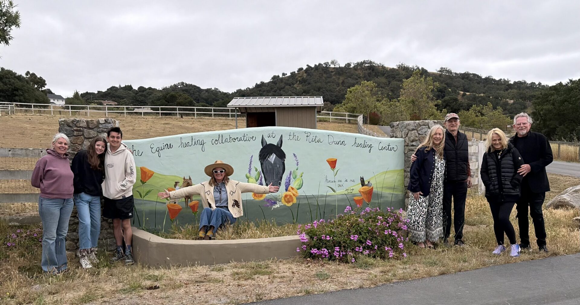 Group posing by painted horse mural at ranch