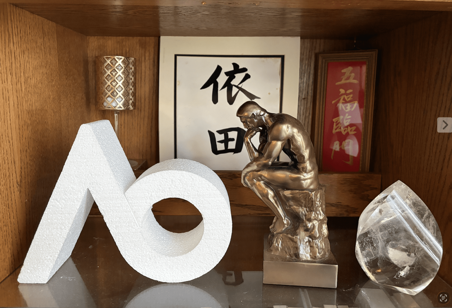Bronze thinker statue, foam letters, crystal on shelf